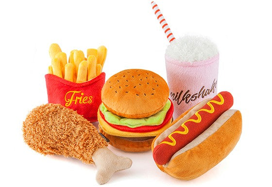 Plush toys resembling fast food items including fries, burger, milkshake, and hot dog on a white background.